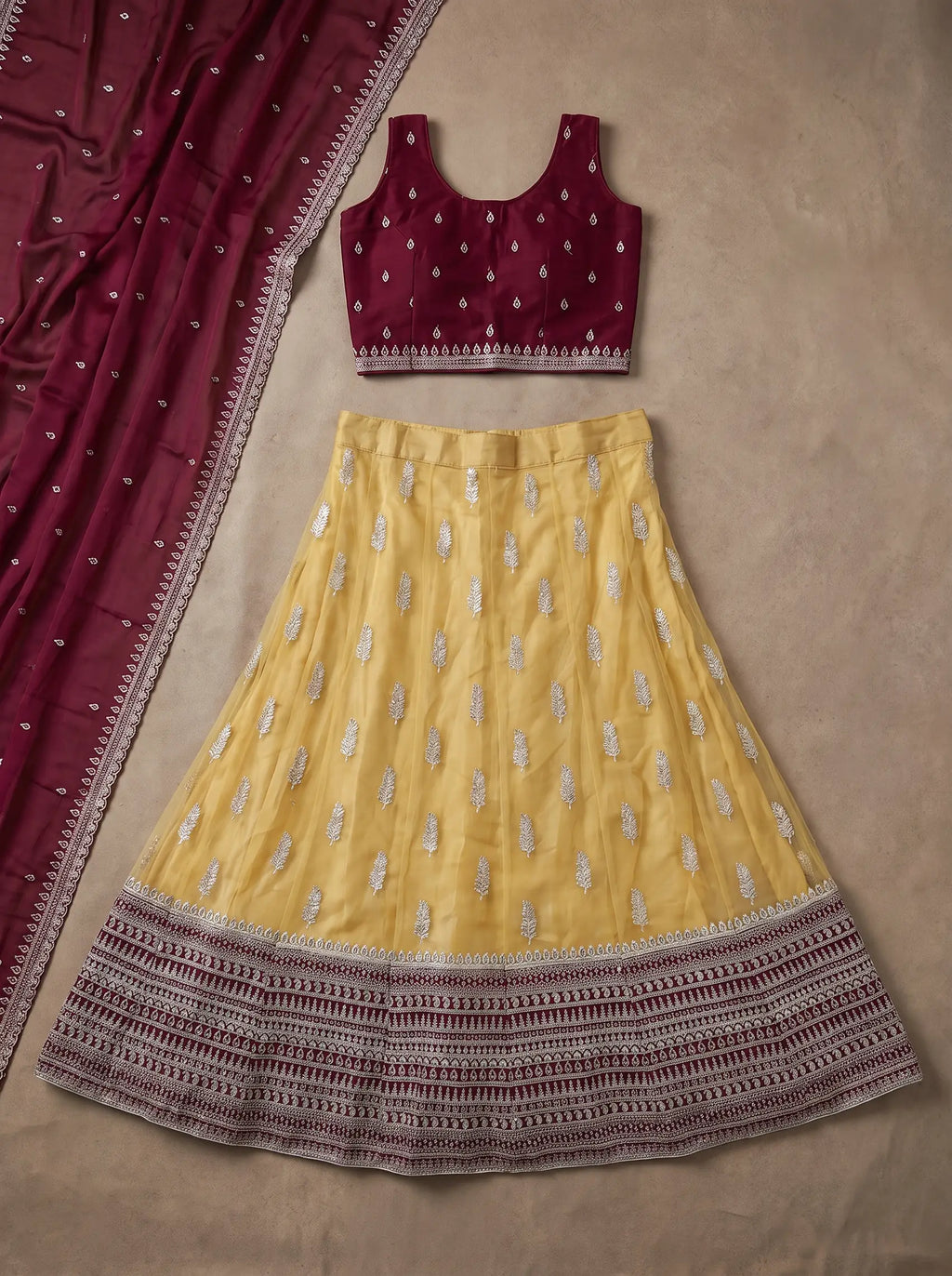 Wine blouse, mustard yellow embroidered lehenga and matching wine dupatta displayed flat