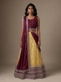Model wearing a wine and mustard yellow embroidered lehenga set with matching wine dupatta