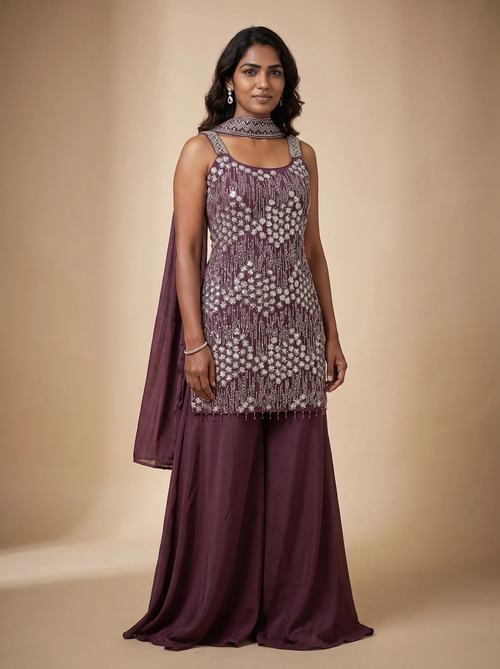 Model wearing a burgundy georgette sharara set with floral-inspired sequin and bead embellished top and matching dupatta