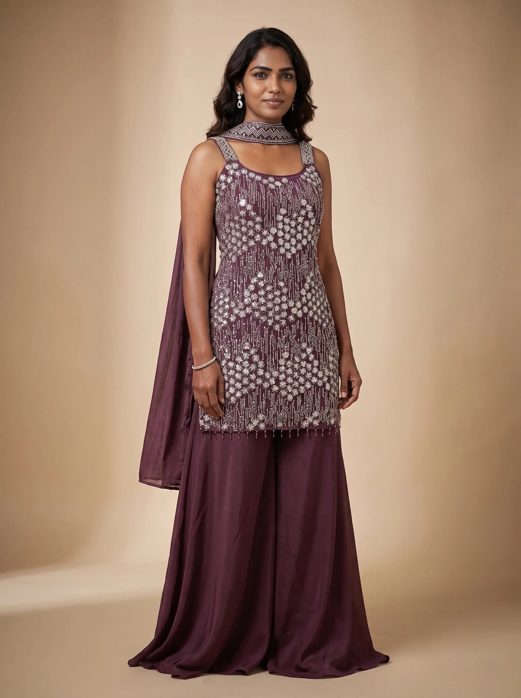 Model wearing a burgundy georgette sharara set with floral-inspired sequin and bead embellished top and matching dupatta