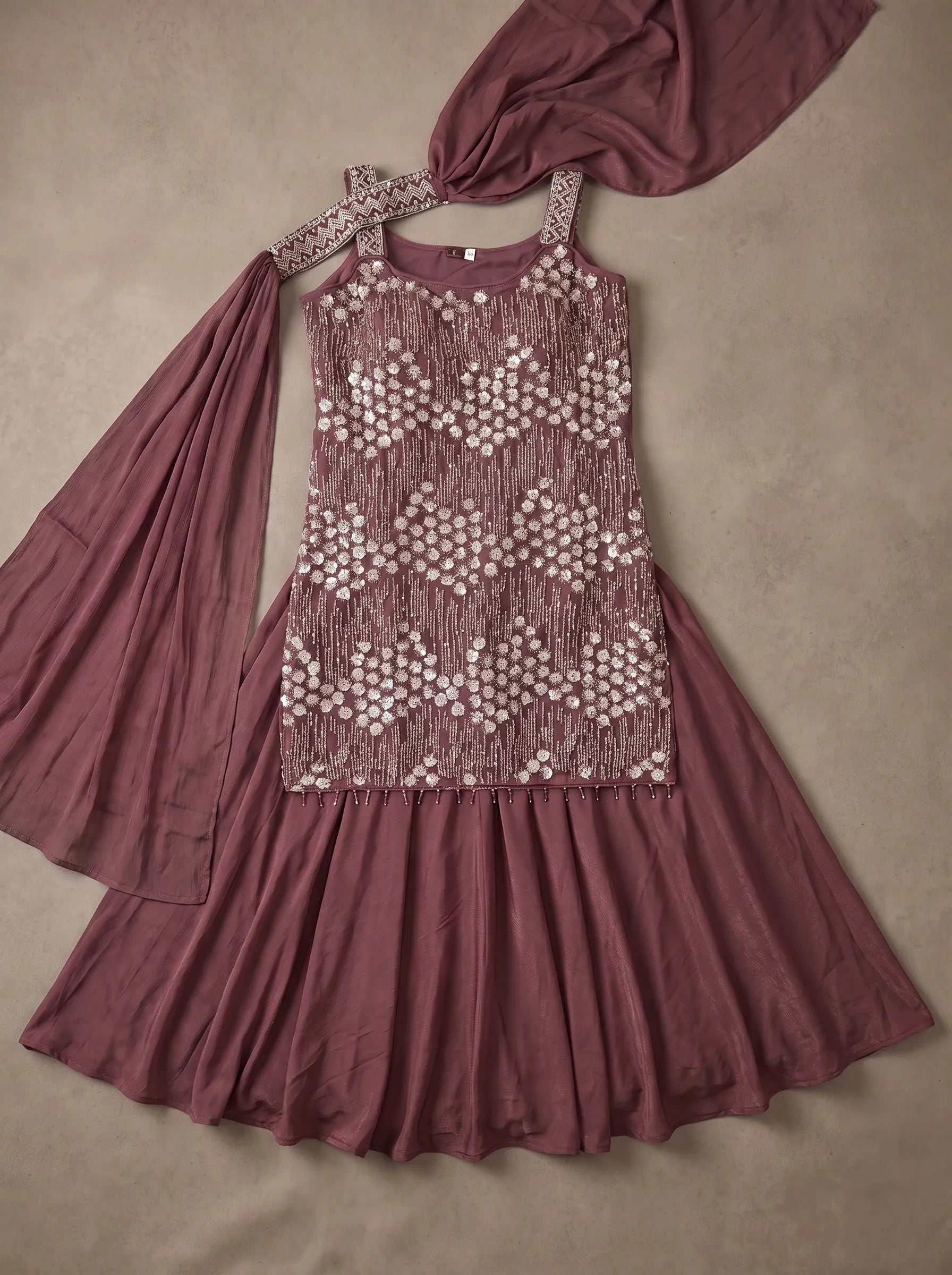 Flat lay of burgundy georgette sharara set with embellished top, flared sharara and matching dupatta