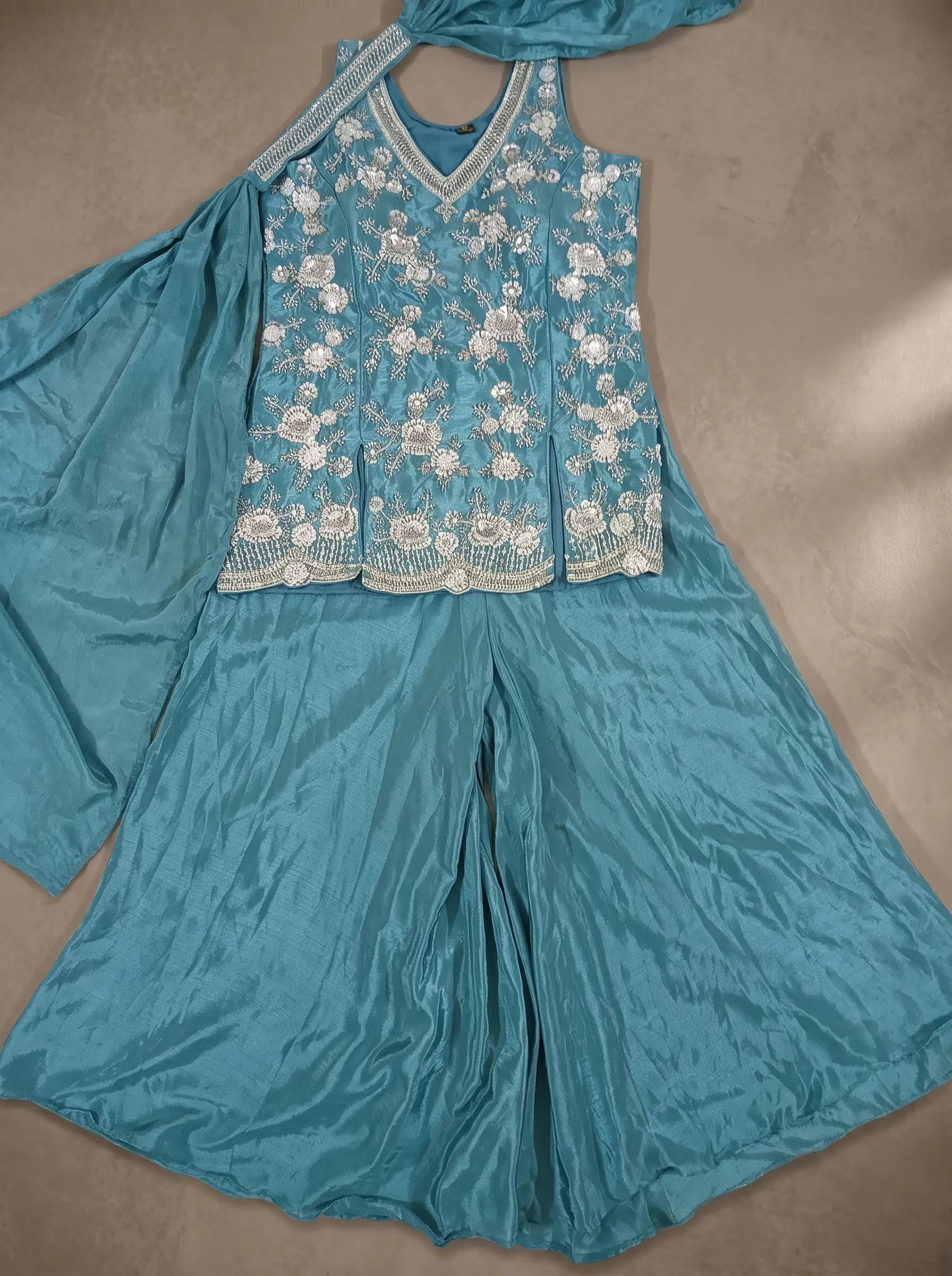 Teal blue georgette floral sequin and cut-bead sharara set displayed flat with matching dupatta