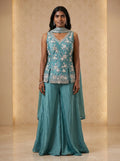 Model wearing a teal blue georgette floral sequin and cut-bead sharara set with matching dupatta