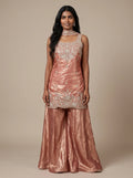 Model wearing a peach tissue silk embroidered sharara set with flared bottoms and matching dupatta.