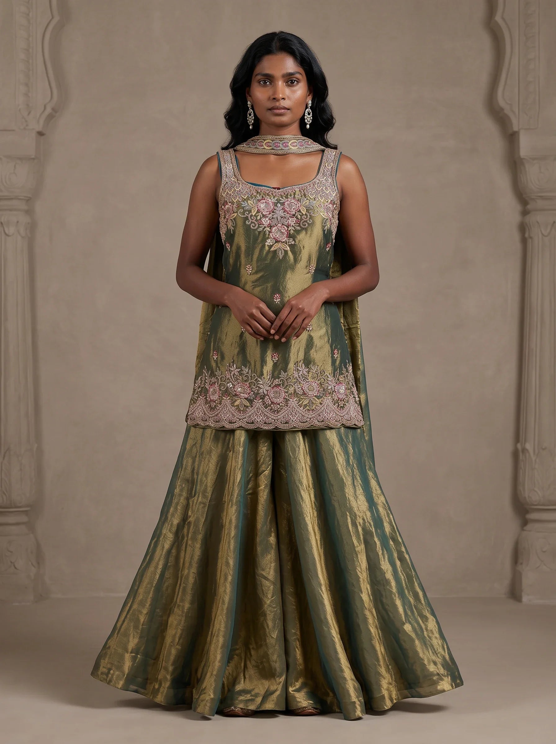 Model wearing olive green tissue silk embroidered sharara set with metallic gold sheen and matching dupatta