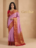 Model wearing a lilac pink soft silk saree with gold-toned woven motifs and a wide reddish zari border