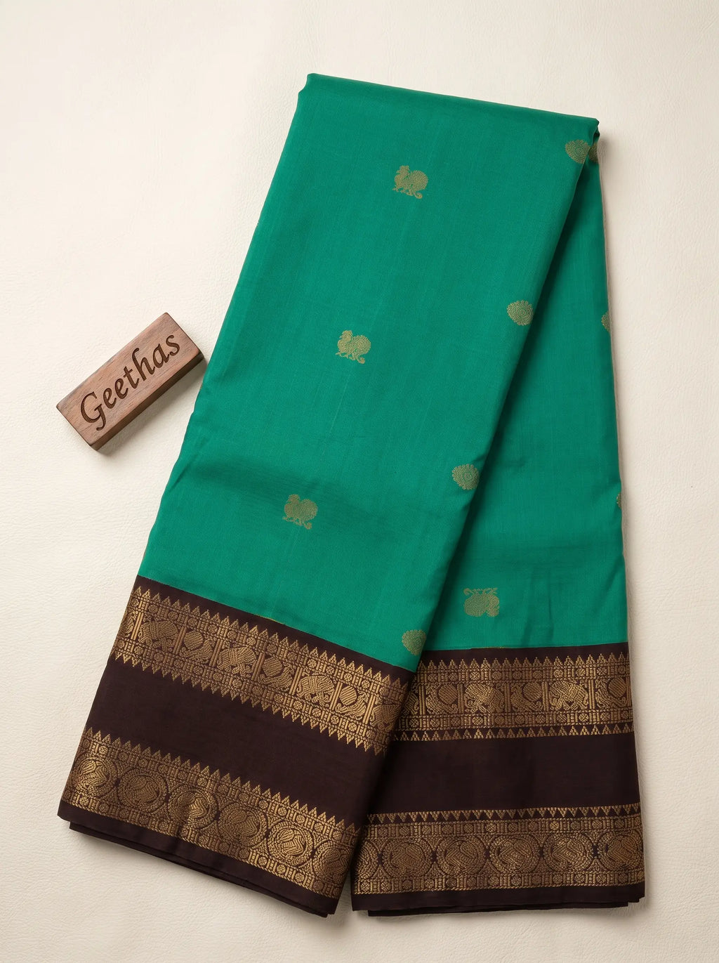 Bottle green soft silk saree with scattered gold-toned motifs and deep maroon woven border