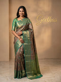 Model wearing a beige-gold floral woven saree with a teal-green and gold-toned border